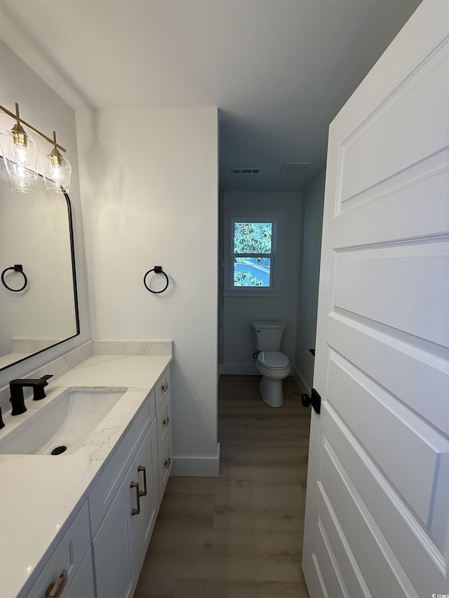 bathroom featuring visible vents, vanity, wood finished floors, toilet, and baseboards