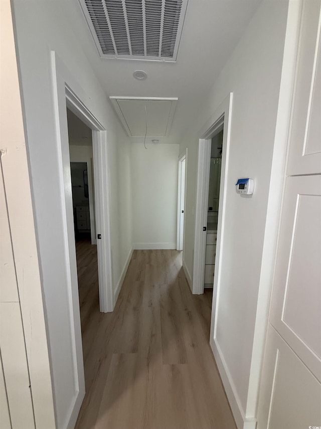 hallway featuring baseboards, attic access, light wood-type flooring, and visible vents