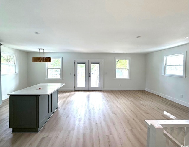 unfurnished living room featuring baseboards, french doors, and light wood-style floors