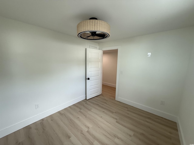 spare room featuring baseboards and light wood-type flooring