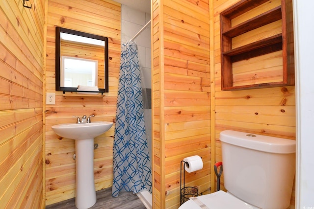bathroom with wooden walls, a shower with shower curtain, and toilet