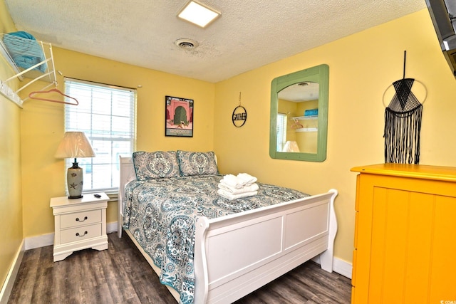 bedroom featuring a textured ceiling, visible vents, dark wood-style flooring, and baseboards