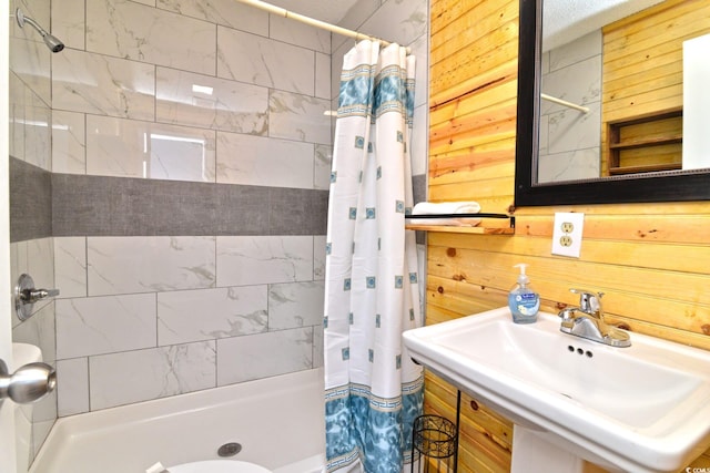 full bathroom featuring a shower stall, wooden walls, and a sink