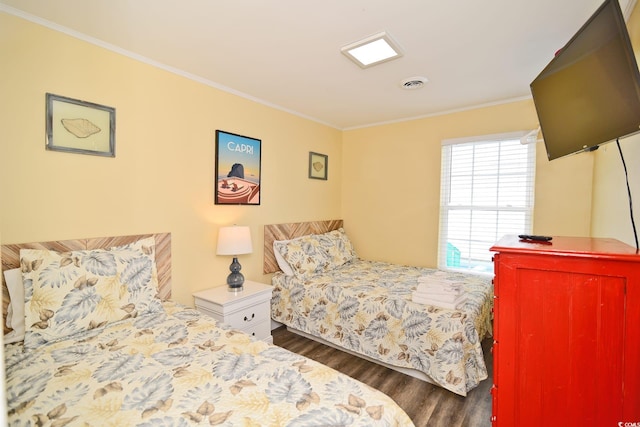 bedroom with visible vents, crown molding, and wood finished floors
