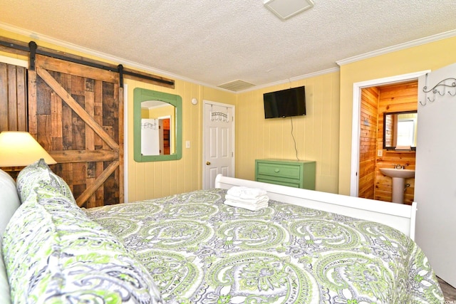 bedroom with crown molding, a textured ceiling, a barn door, and a sink