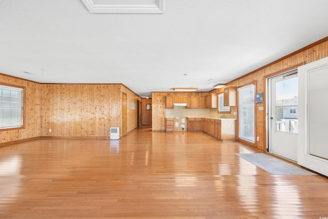 unfurnished living room featuring light wood finished floors and wooden walls