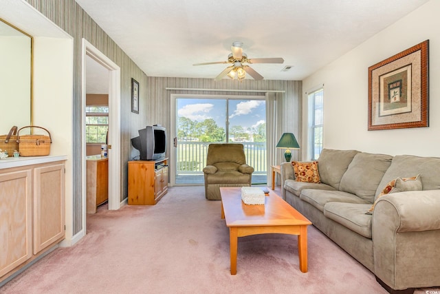living area featuring visible vents, ceiling fan, and light colored carpet