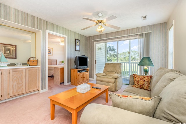 living room with wallpapered walls, baseboards, ceiling fan, visible vents, and light colored carpet