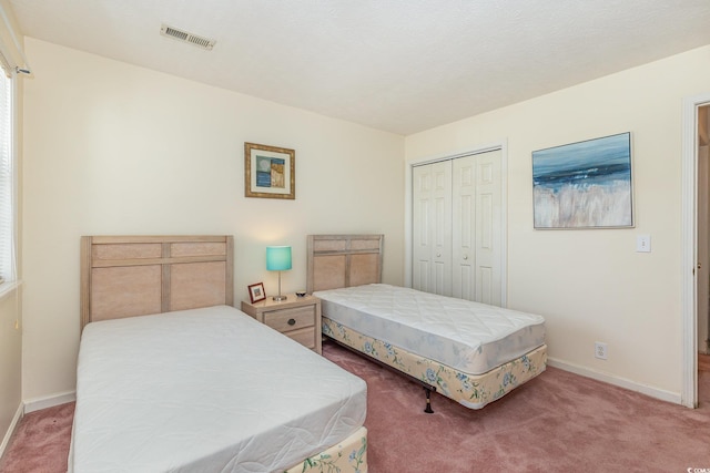 carpeted bedroom with a closet, visible vents, and baseboards