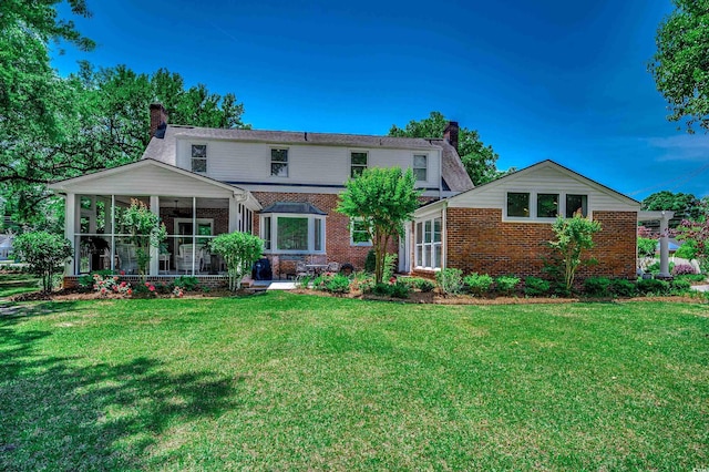 402 E Broad St, Hemingway, SC 29554 - back of house with a chimney, a sunroom, brick siding, and a lawn