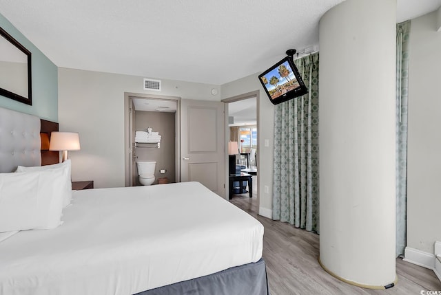 107 S Ocean Blvd Unit 1001, Myrtle Beach, SC 29577 - bedroom featuring baseboards, ensuite bath, light wood finished floors, and visible vents