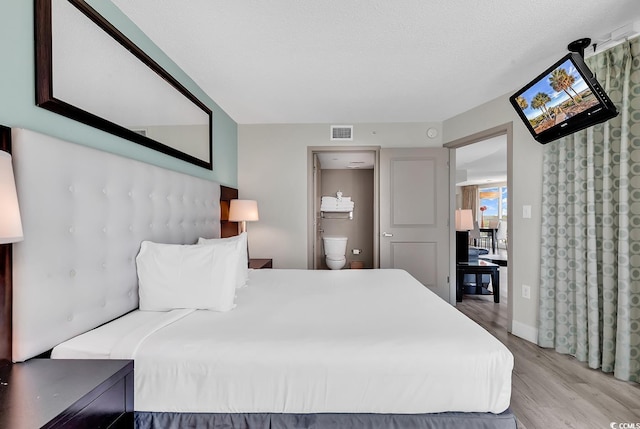 107 S Ocean Blvd Unit 1001, Myrtle Beach, SC 29577 - bedroom with connected bathroom, visible vents, and wood finished floors