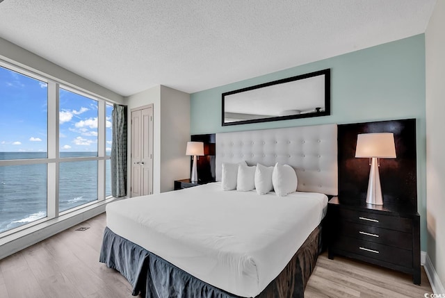 107 S Ocean Blvd Unit 1001, Myrtle Beach, SC 29577 - bedroom with a textured ceiling, a water view, and light wood-type flooring