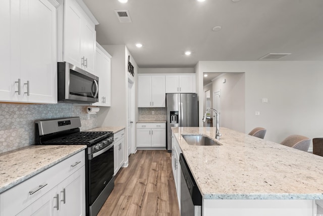 4609 Day Lily Run St, Myrtle Beach, SC 29579 - kitchen featuring appliances with stainless steel finishes, a sink, a kitchen island with sink, light wood-style floors, and white cabinets