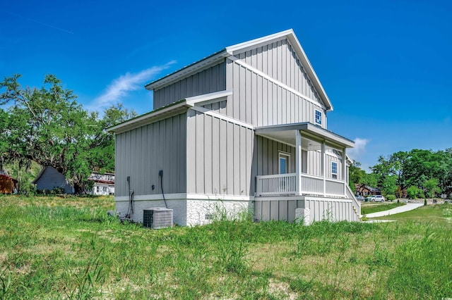 view of home's exterior with board and batten siding, cooling unit, and covered porch