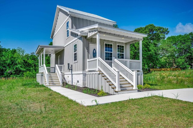 view of front of house featuring covered porch, stairs, a front yard, and board and batten siding
