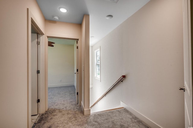 hallway with carpet, baseboards, and an upstairs landing