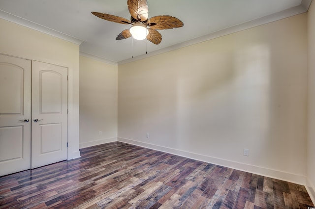 unfurnished bedroom with a ceiling fan, a closet, dark wood-style flooring, baseboards, and ornamental molding