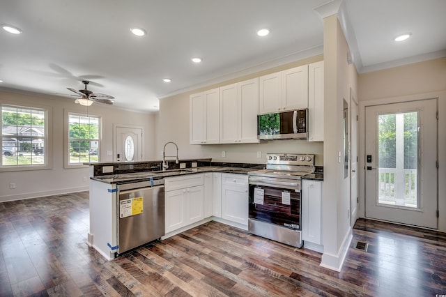 kitchen with a sink, a peninsula, stainless steel appliances, visible vents, and crown molding