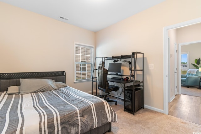 bedroom with visible vents, baseboards, and light carpet