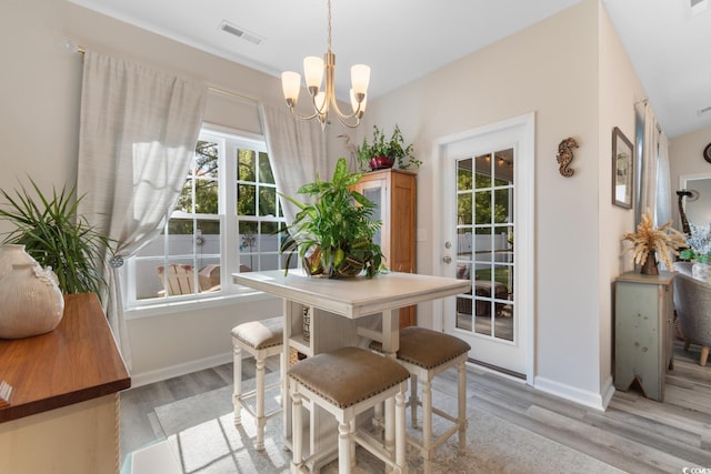 dining space with light wood finished floors, an inviting chandelier, visible vents, and baseboards