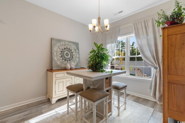 dining space featuring baseboards, light wood-style floors, a chandelier, and visible vents
