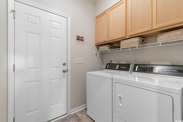 clothes washing area featuring cabinet space, washing machine and clothes dryer, light wood-type flooring, and baseboards