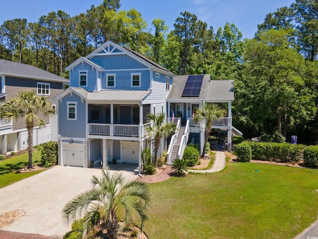 coastal inspired home with concrete driveway, board and batten siding, a front lawn, stairway, and solar panels