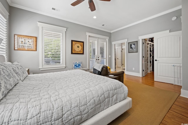 bedroom with multiple windows, crown molding, visible vents, and wood finished floors