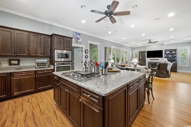 kitchen featuring light wood-style flooring, a ceiling fan, appliances with stainless steel finishes, ornamental molding, and recessed lighting