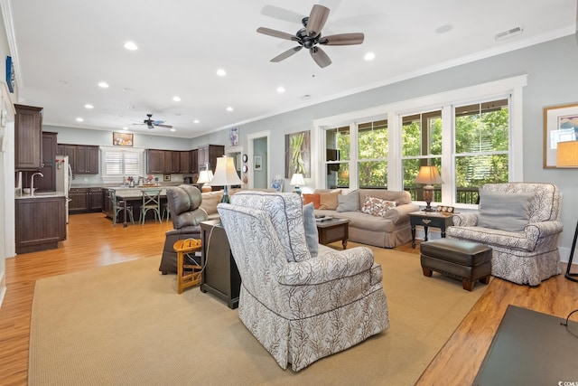 living room featuring ornamental molding, visible vents, and ceiling fan