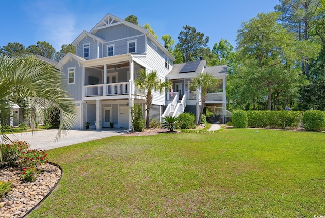 raised beach house featuring board and batten siding, solar panels, a front yard, and ceiling fan
