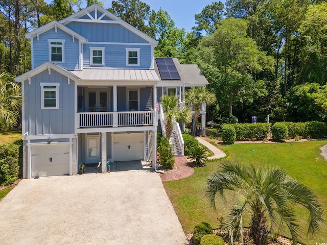 coastal home featuring board and batten siding, driveway, a standing seam roof, an attached garage, and a front lawn