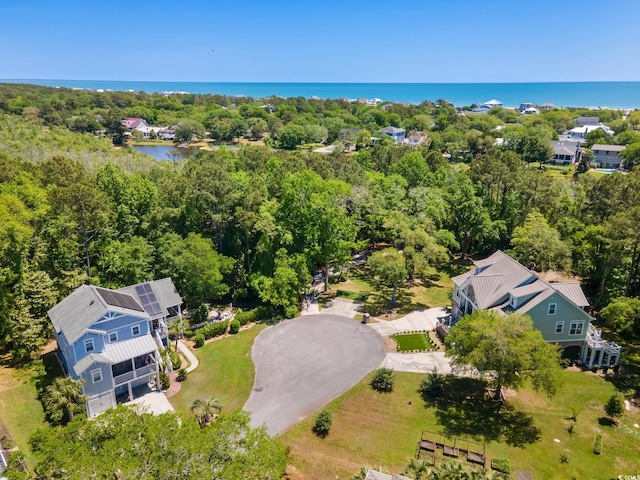 drone / aerial view featuring a wooded view and a water view