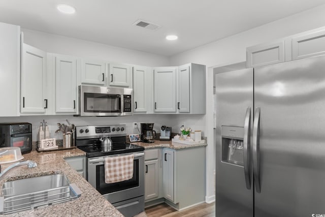 1123 Fairway Ln Unit 1123, Conway, SC 29526 - kitchen featuring light stone counters, light wood finished floors, visible vents, a sink, and stainless steel appliances