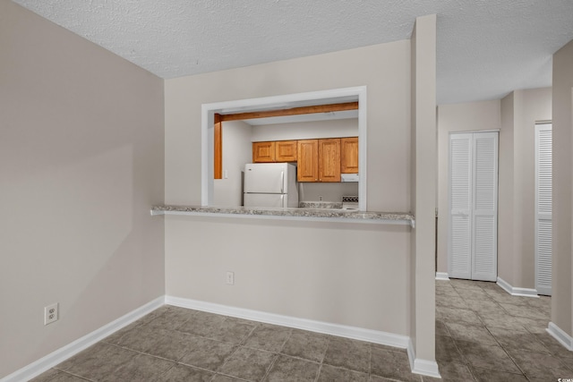 900 Courtyard Dr Unit K7, Myrtle Beach, SC 29577 - kitchen with freestanding refrigerator, a textured ceiling, baseboards, tile patterned floors, and brown cabinets