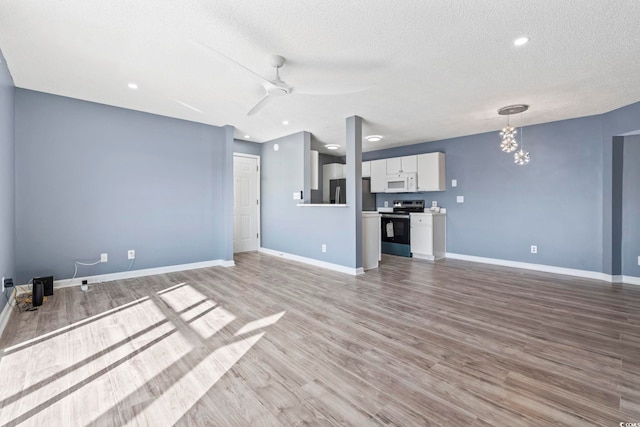 2258 Essex Dr Unit G, Surfside Beach, SC 29575 - unfurnished living room with a textured ceiling, baseboards, light wood-style flooring, and ceiling fan with notable chandelier