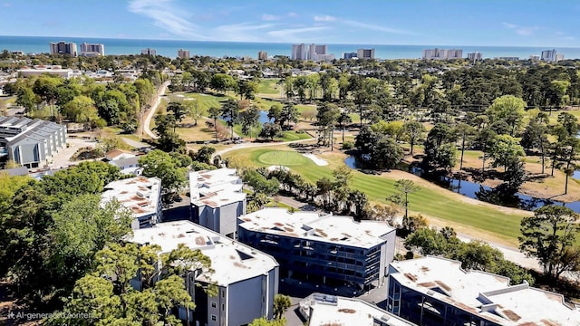 view of urban area featuring a golf course, a large body of water, and a tree filled landscape