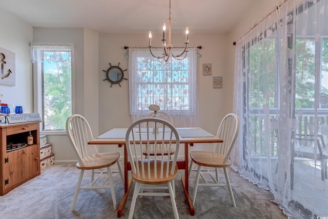 dining area featuring a chandelier, light colored carpet, and baseboards