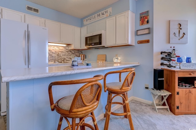 kitchen featuring freestanding refrigerator, light colored carpet, white cabinetry, and light countertops