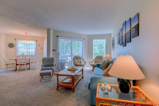 carpeted living room featuring healthy amount of natural light, a textured ceiling, a chandelier, and baseboards