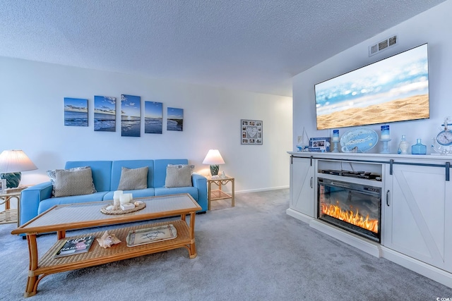 carpeted living area with a glass covered fireplace and a textured ceiling