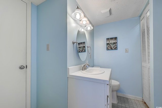 bathroom with toilet, vanity, a closet, tile patterned floors, and baseboards