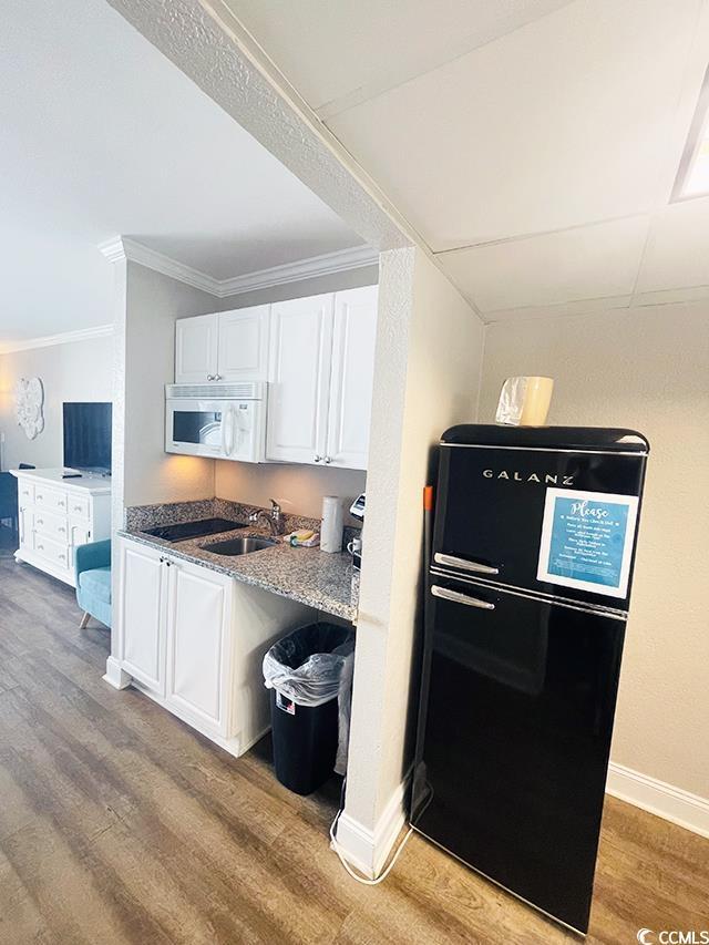 201 N Ocean Blvd Unit 2536, Myrtle Beach, SC 29572 - kitchen with white microwave, light wood finished floors, crown molding, freestanding refrigerator, and white cabinets