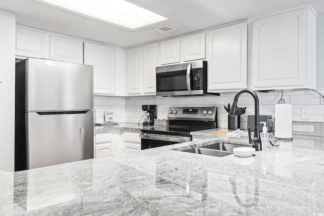 205 74th Ave N Unit 1104, Myrtle Beach, SC 29572 - kitchen featuring stainless steel appliances, a sink, white cabinetry, light stone counters, and decorative backsplash