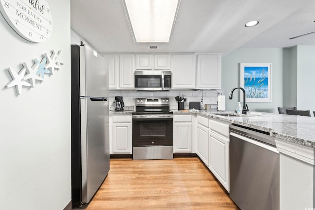 205 74th Ave N Unit 1104, Myrtle Beach, SC 29572 - kitchen featuring appliances with stainless steel finishes, a sink, white cabinetry, light wood-style floors, and light stone counters
