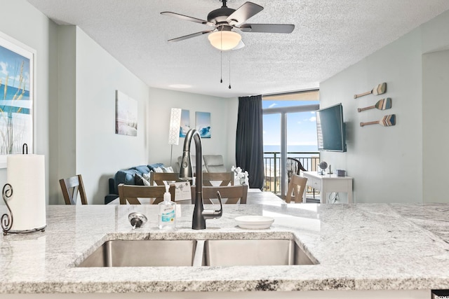 205 74th Ave N Unit 1104, Myrtle Beach, SC 29572 - kitchen with a sink, a textured ceiling, open floor plan, ceiling fan, and light stone counters