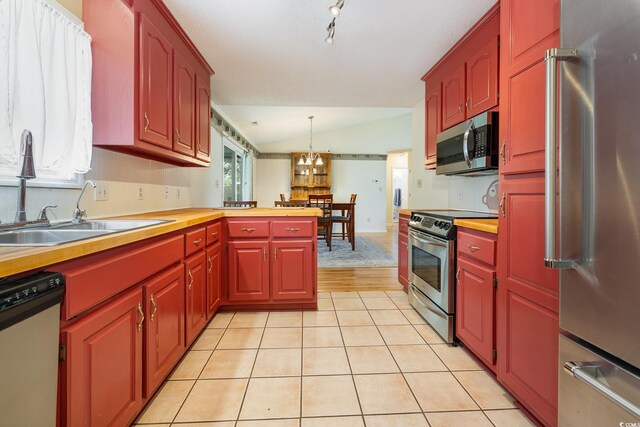 706 Chippendale Dr, Myrtle Beach, SC 29588 - kitchen featuring a sink, stainless steel appliances, vaulted ceiling, light tile patterned floors, and hanging light fixtures
