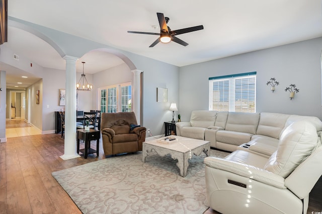 living area with a ceiling fan, ornate columns, light wood-type flooring, baseboards, and arched walkways