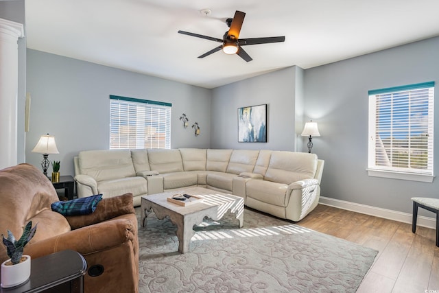 living area featuring a healthy amount of sunlight, baseboards, wood finished floors, and ceiling fan